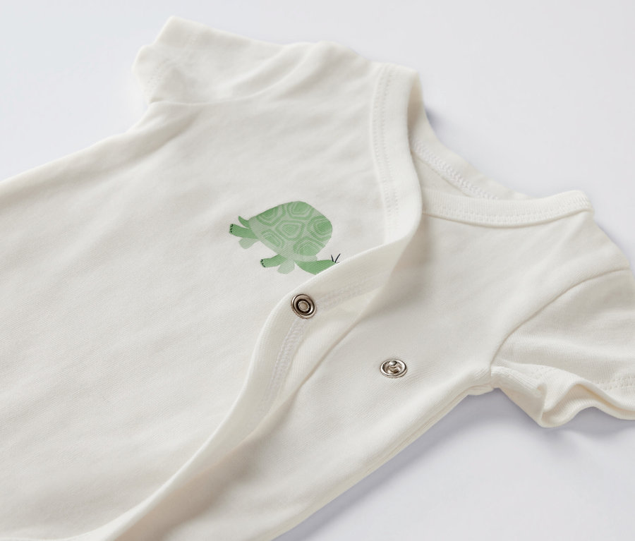 Detailansicht eines weißen Baby-Kurzarmbodys mit Schildkrötenmotiv.