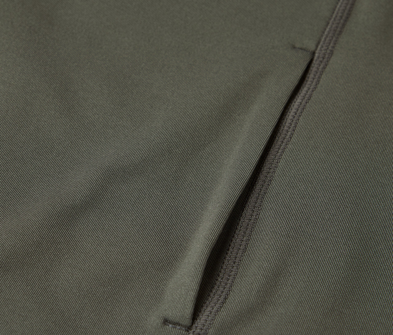 Detailaufnahme eines olivgrünen Stoffes mit einer Reißverschlusstasche.