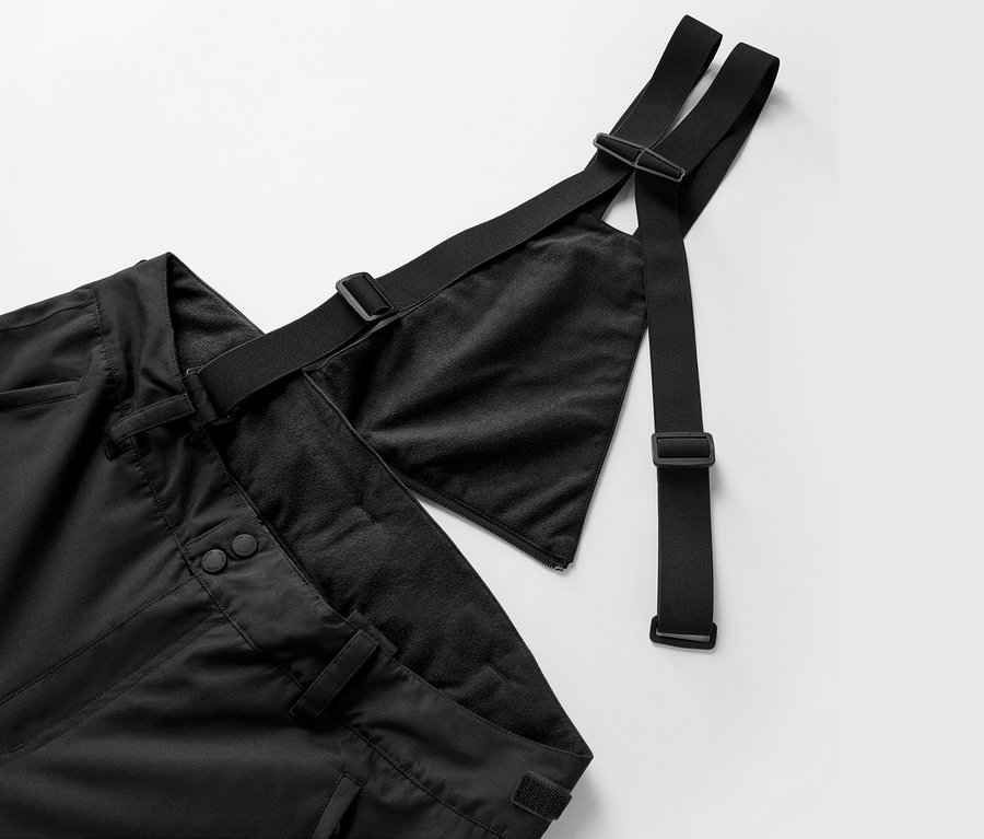 Detailaufnahme einer schwarzen Hose mit Latz und verstellbaren Trägern.