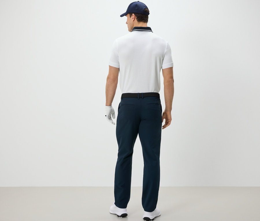 Mann von hinten trägt eine Outdoorhose, ein Poloshirt, eine Kappe und einen Golfhandschuh.