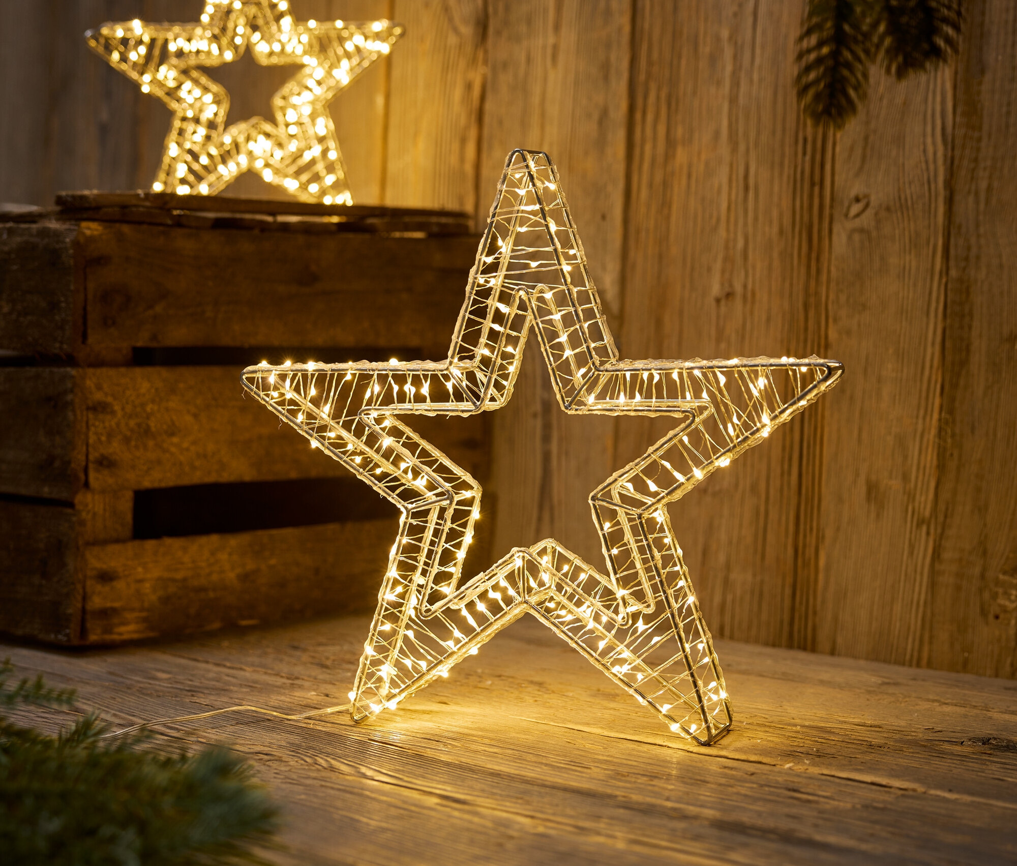 Zwei dekorative Sterne mit LED-Lichtern stehen auf einer Holzoberfläche.