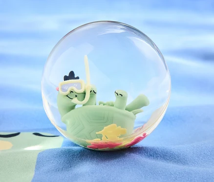 Eine grüne Schildkröte mit Taucherbrille und Schnorchel in einer durchsichtigen Kugel auf blauem Hintergrund. Produkt: XXL-Flummi