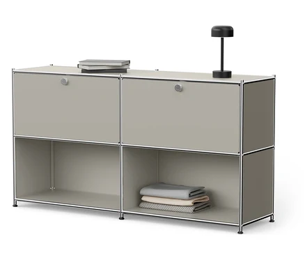 Grauer Schrank mit vier Fächern, Büchern und Lampe.