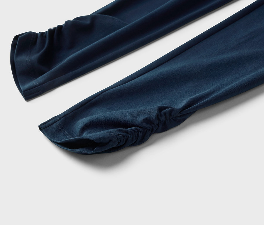 Nahaufnahme von zwei marineblauen Ärmeln mit gerafften Bündchen auf einem weißen Hintergrund.