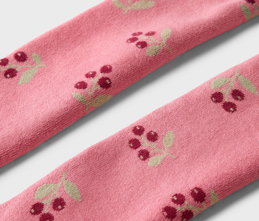 Nahaufnahme von zwei rosa Socken mit einem Muster aus roten Beeren und Blättern.