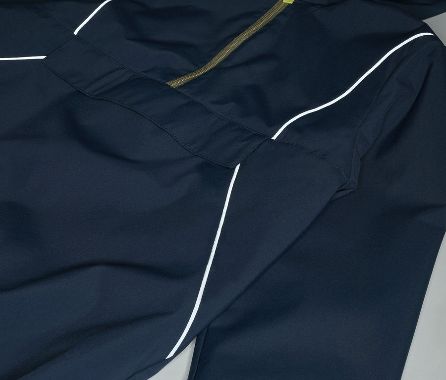 Nahaufnahme einer marineblauen Jacke mit Kapuze und weißem Streifen, die mit einem olivgrünen Reißverschluss geschlossen wird.