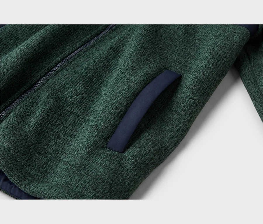 Nahaufnahme einer dunkelgrünen, melierten Fleecejacke mit dunklem Reißverschluss links und dunkelblau eingefasster Taschenöffnung rechts.