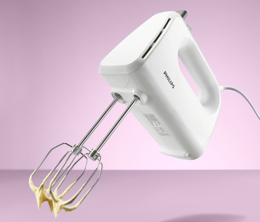 Weißer Philips-Handmixer HR 3706 mit Edelstahl-Rührbesen, an denen gelber Teig hängt.