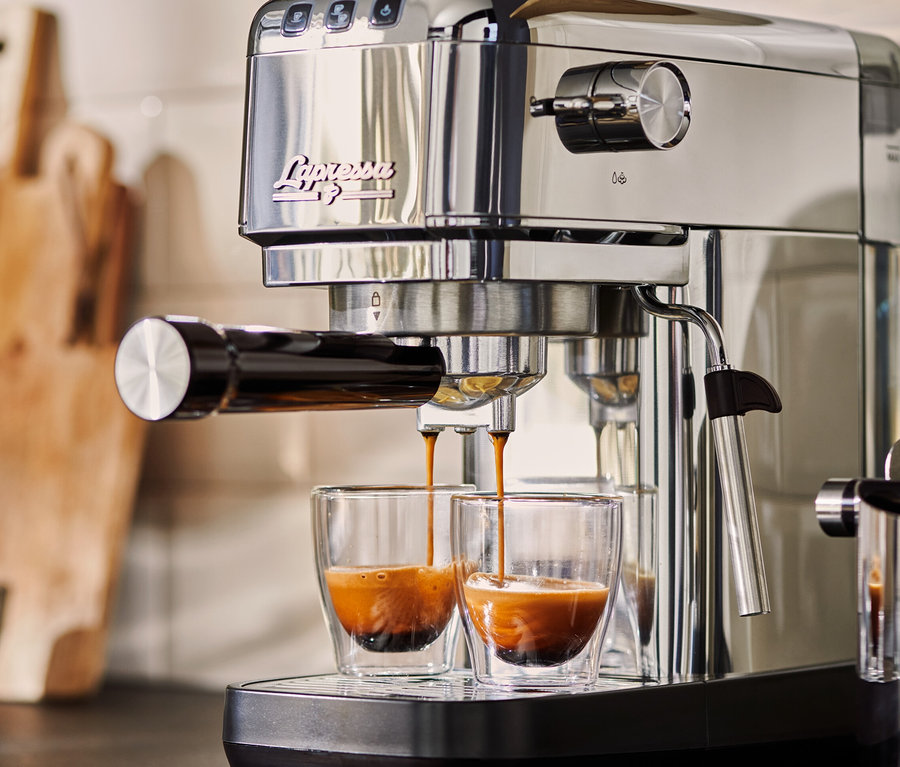 Eine silberne »Lapressa« Siebträgermaschine bereitet Espresso in zwei Glasbechern zu.