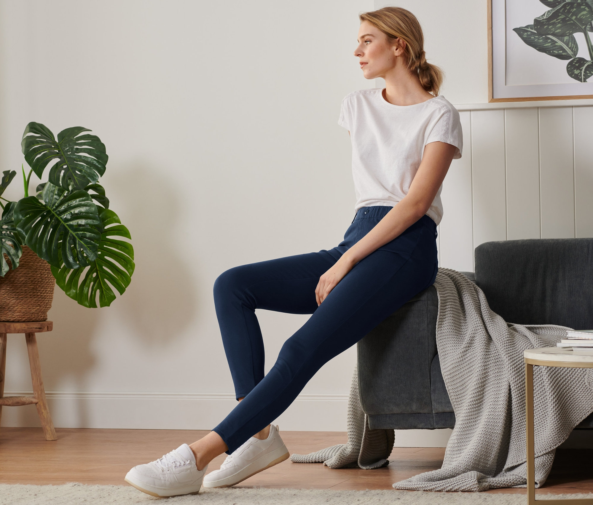 Frau sitzt auf Sofa und trägt Jeggings.