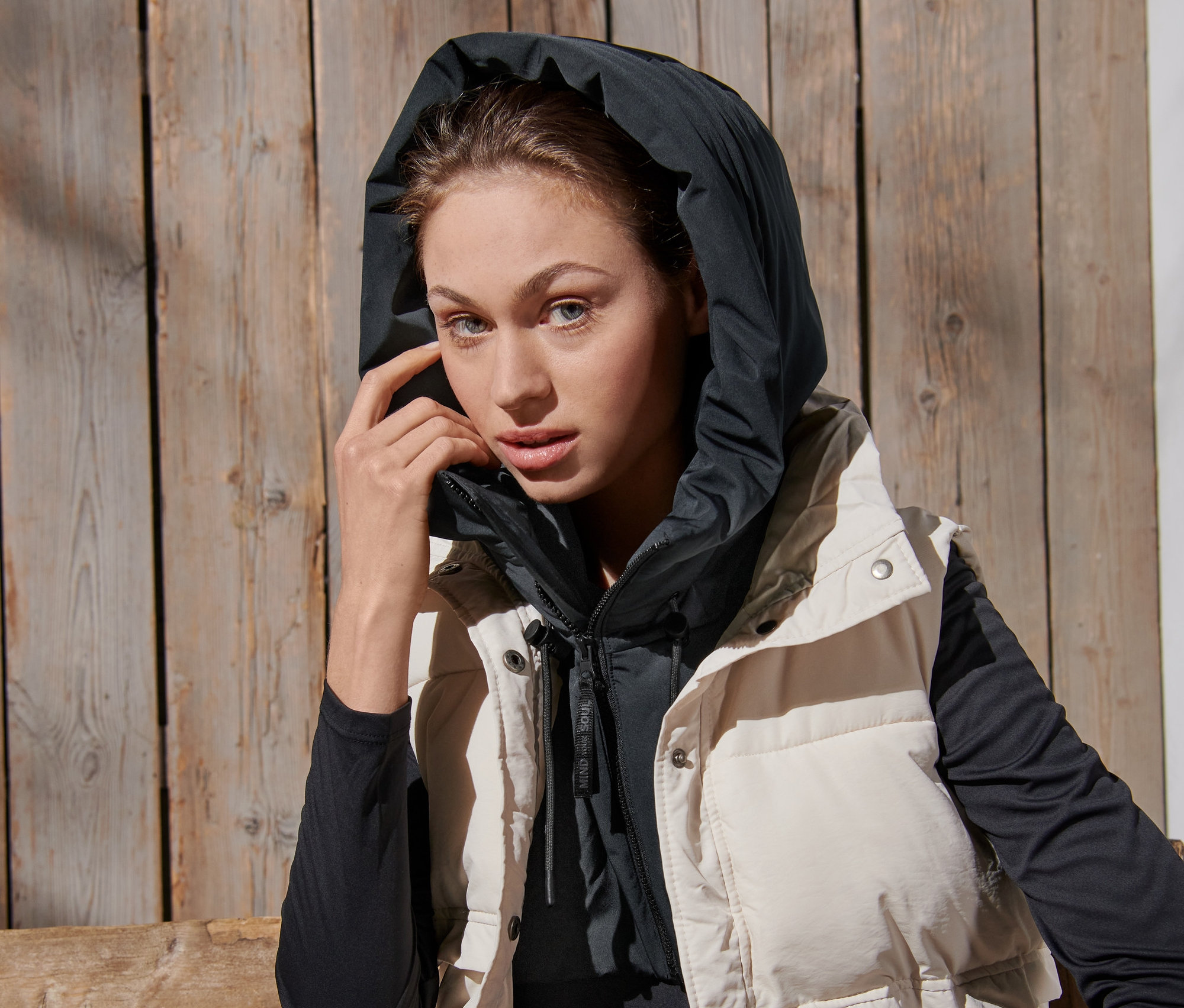 Frau trägt eine wattierte Kapuze mit Stehkragen und eine Weste.