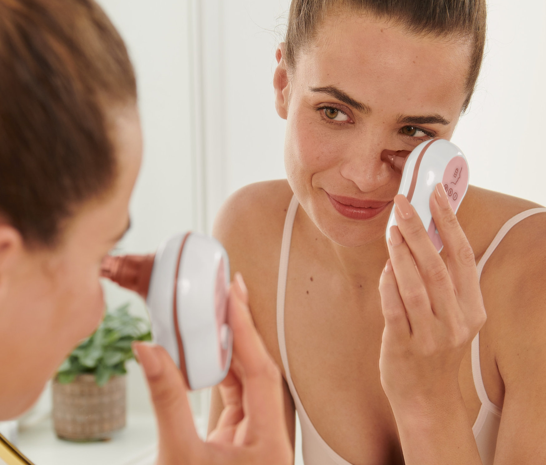 Frau benutzt Porenreiniger auf Gesicht vor Spiegel.