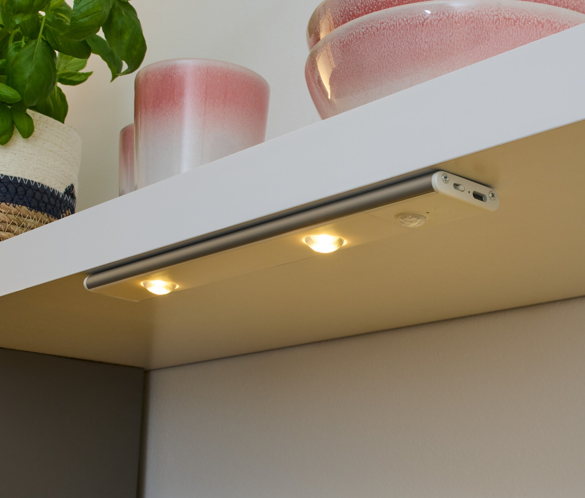 Eine LED-Akku-Multifunktionsleuchte ist unter einem Regal befestigt und beleuchtet eine Arbeitsfläche.