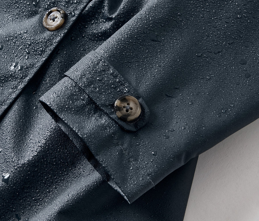 Detailaufnahme eines Kinder-Allwetter-Trenchcoats mit Wassertropfen.