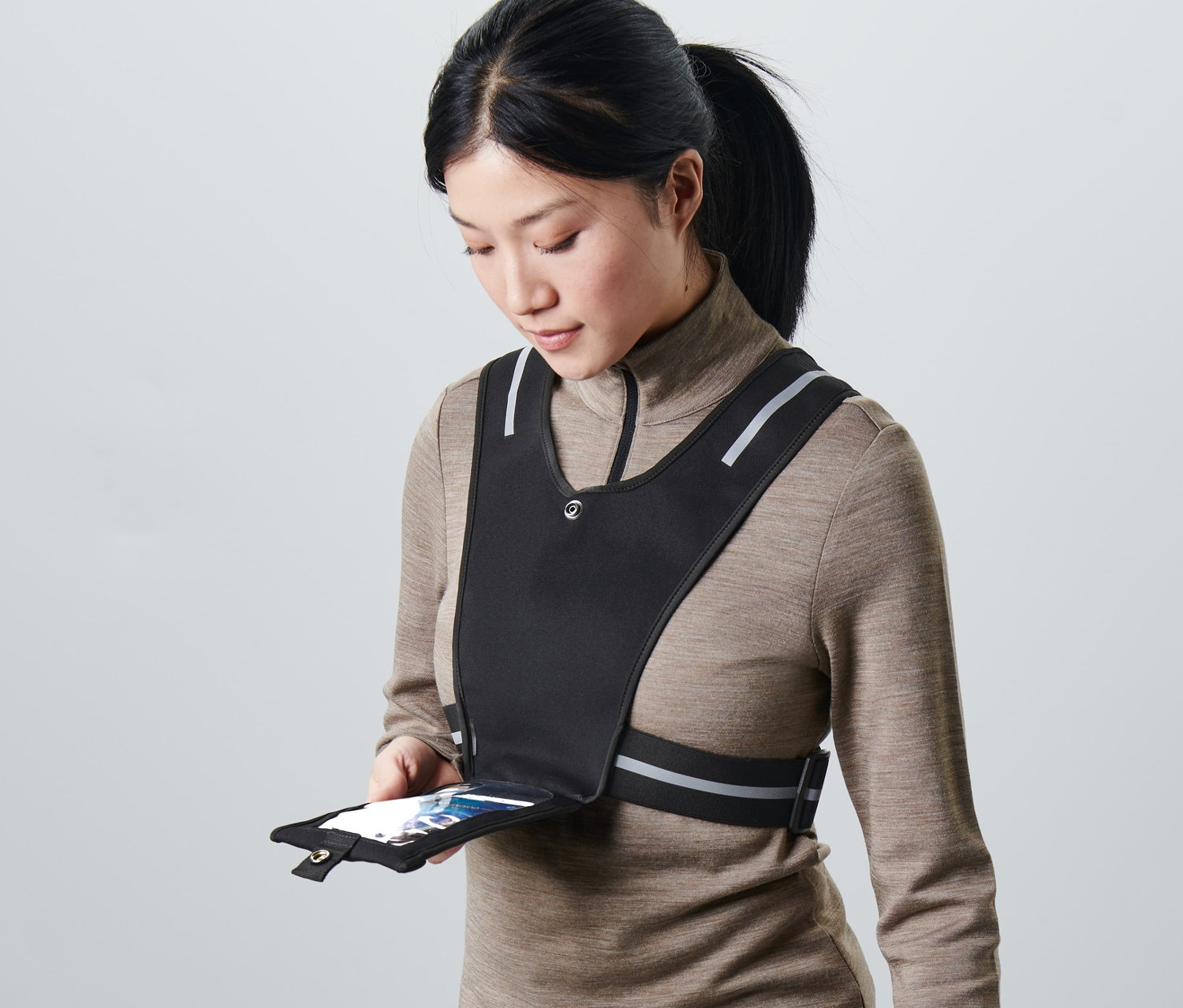 Frau hält Smartphone in der Tasche einer schwarzen Laufweste.