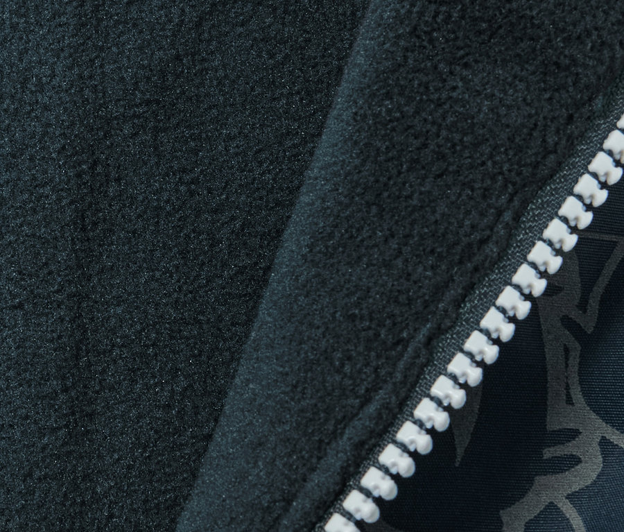 Detailaufnahme einer dunkelblauen Kinder Thermo-Regenhose mit reflektierenden Elementen und einem weißen Reißverschluss.