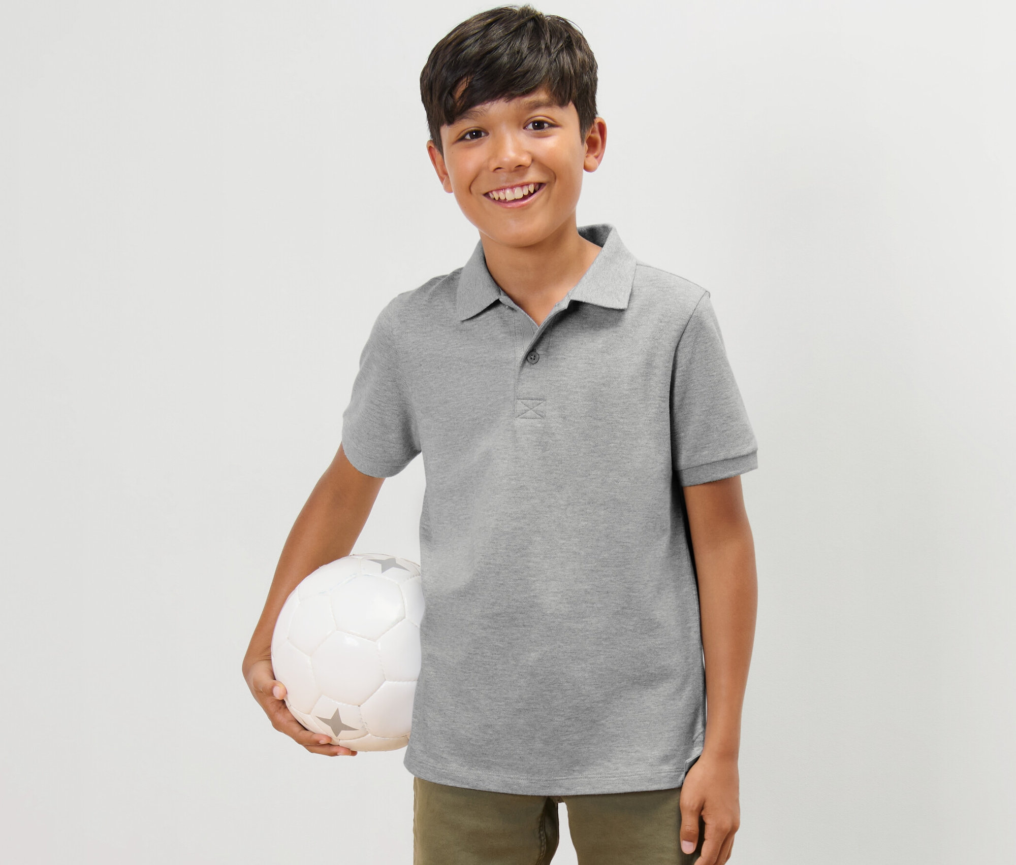 Ein Junge hält einen Fußball und trägt ein graues Polo-Shirt. 2 Kinder-Poloshirts aus Baumwoll-Piqué