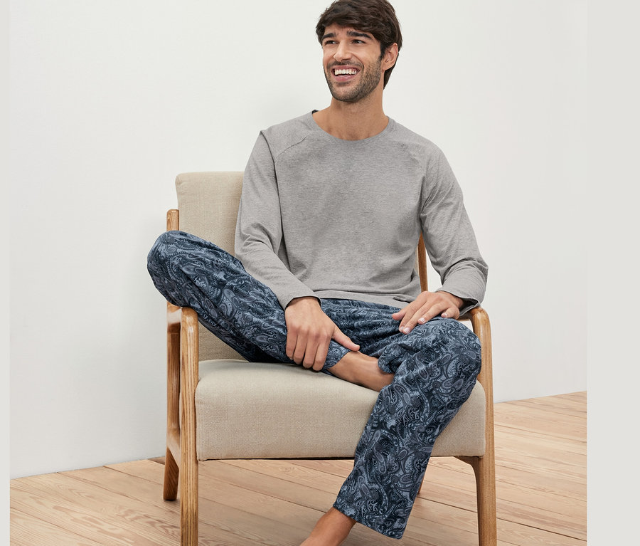 Mann sitzt im Sessel und trägt ein Pyjama-Set.