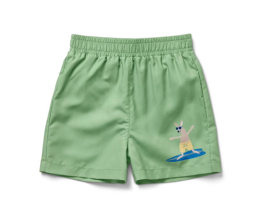Grüne Kinder-Boardshorts mit Känguru-Aufdruck beim Wellenreiten.
