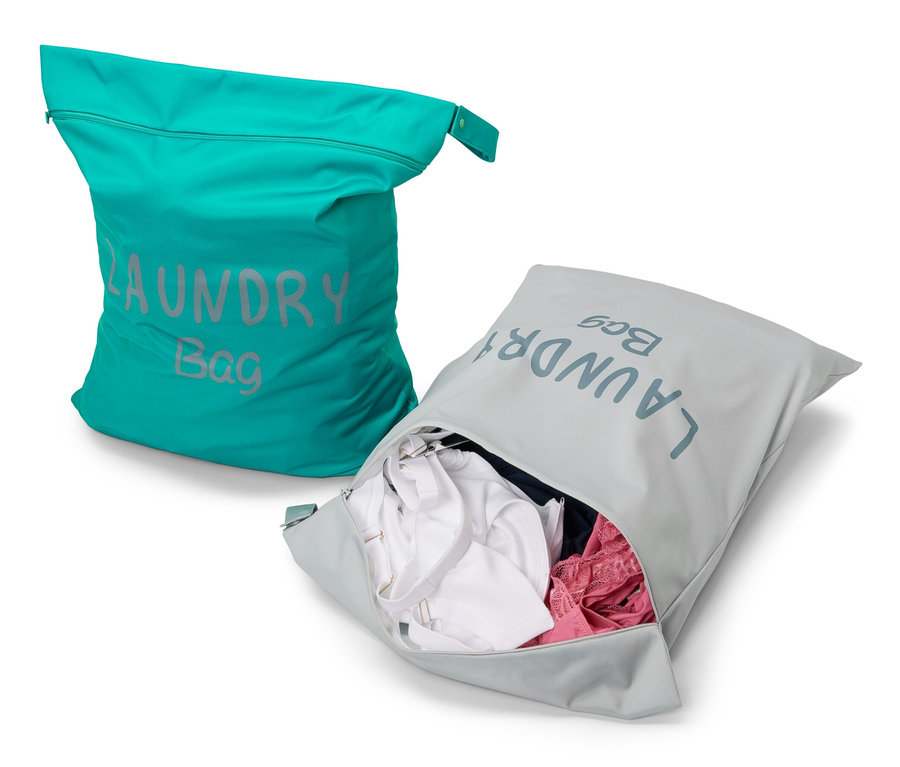 Zwei Reise-Schmutzwäschebeutel: ein türkiser und ein grauer mit Wäsche.