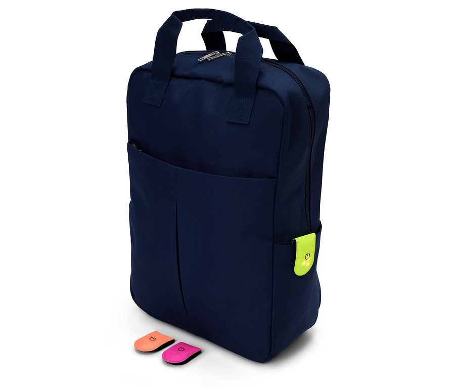 Ein marineblauer Rucksack mit einem neongrünen Anhänger und zwei farbigen Anstecknadeln auf weißem Hintergrund.