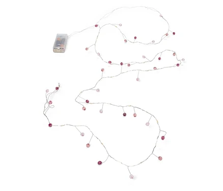 Lichterkette mit kleinen rosa Perlen und Batteriepack auf weißem Hintergrund.