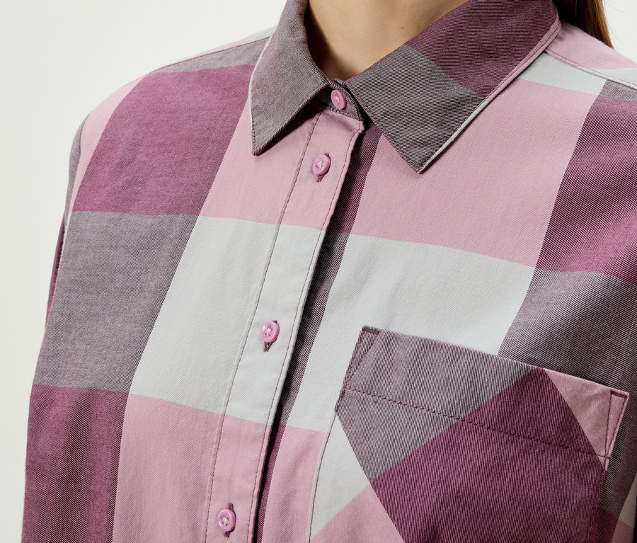 Detail eines karierten Damenoberteils mit Knöpfen und Brusttasche.