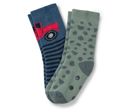 Zwei Kindersocken: eine blaue Socke mit rotem Lastwagen und schwarz-blauen Streifen, die andere grün mit dunkelgrünen Flecken.