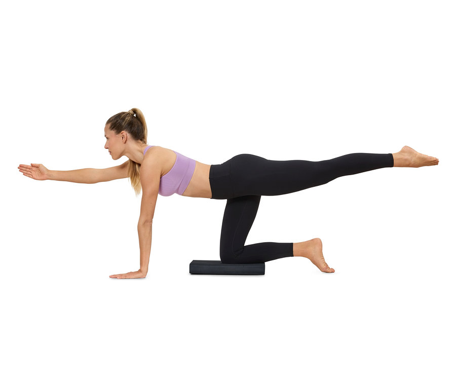 Eine Frau macht Yoga auf einer Matte und trägt Sportbekleidung.