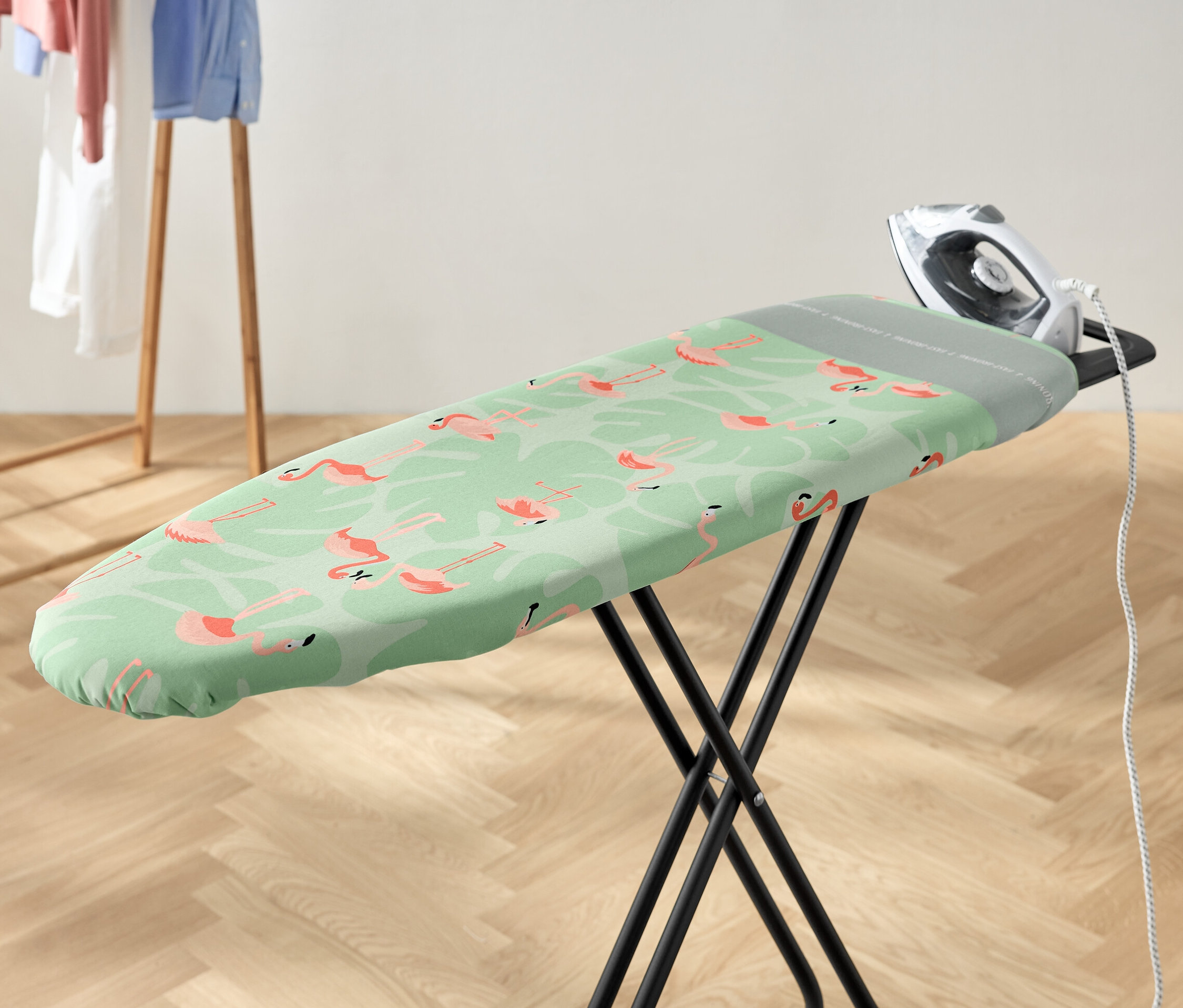 Ein Bügeleisen liegt auf einem Bügelbrett mit einem Bügelbrettbezug mit Flamingomuster.
