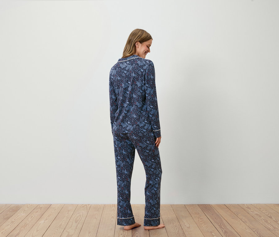 Frau steht mit dem Rücken zum Betrachter und trägt einen dunkelblauen Pyjama mit Aufdruck.