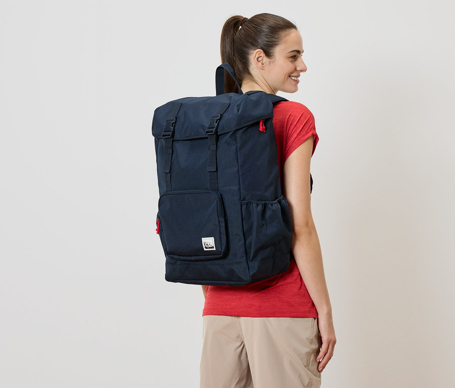 Eine Frau trägt einen dunkelblauen Rucksack mit roten Akzenten.