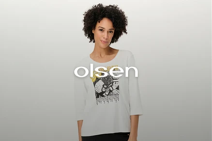 Frau mit lockigem Haar trägt ein weißes Langarmshirt mit Blumenmuster.