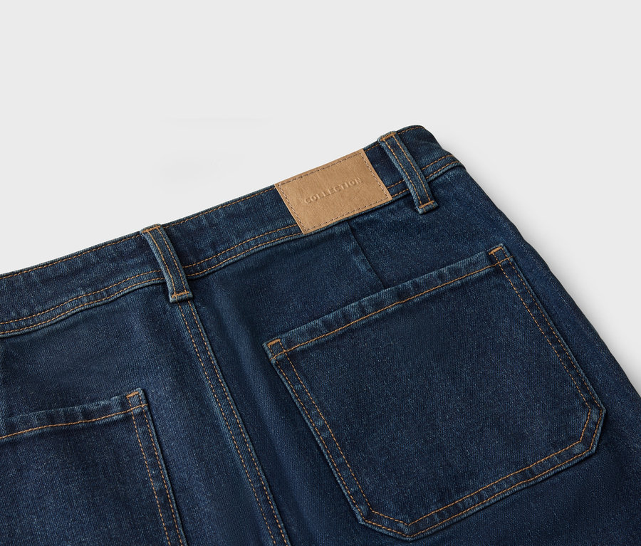 Nahaufnahme der Rückseite einer dunkelblauen Jeans mit aufgesetzten Taschen und einem braunen Lederpatch mit der Aufschrift "Collection".