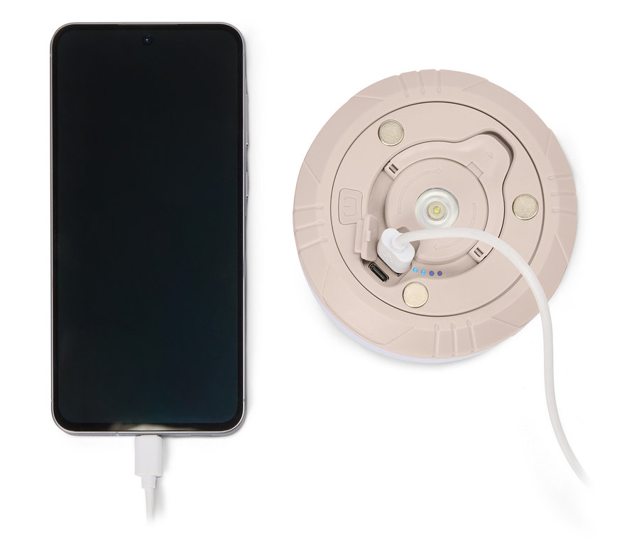 Handy wird mit einem beigen, runden Ladegerät mit weißem Kabel aufgeladen.