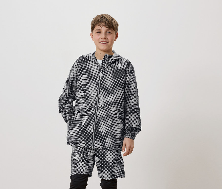 Ein junger Mann trägt eine Kapuzenjacke mit Punktmuster und passende Shorts.