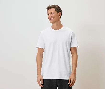 Ein Mann mit hellbraunen Haaren und einem weißen T-Shirt blickt nach rechts.