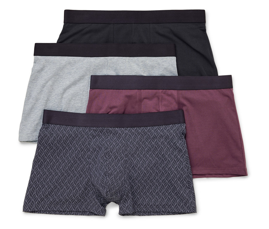 Vier Herren Boxershorts in Schwarz, Grau, Burgunderrot und mit Blattmuster liegen übereinander.