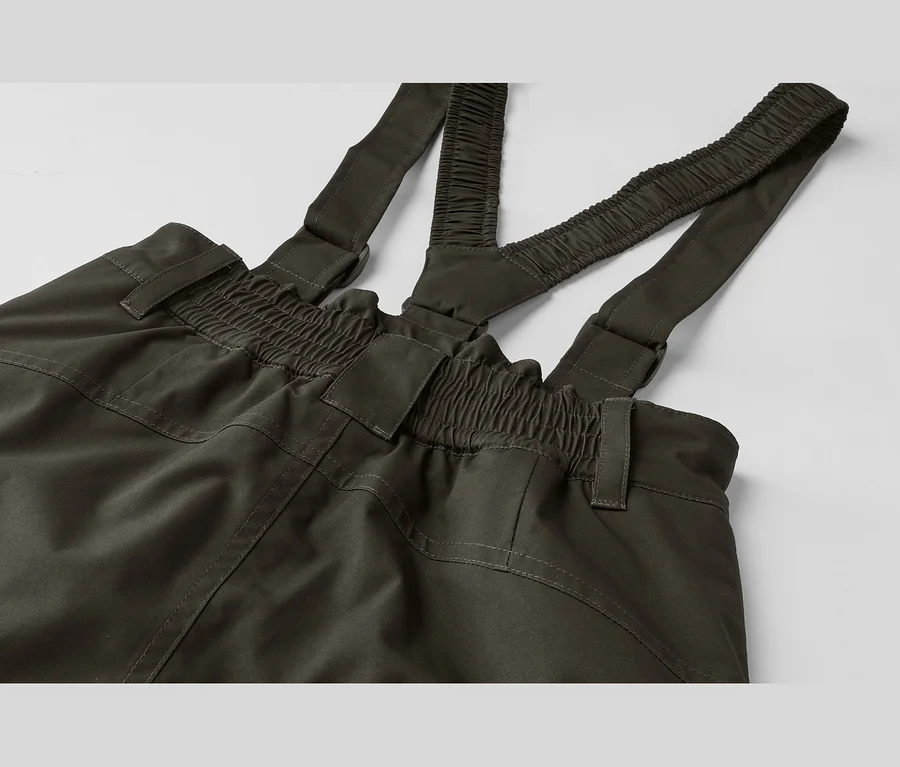 Dunkelgrüne Latzhose mit elastischem Bund und verstellbaren Trägern, auf einem hellen Hintergrund liegend.