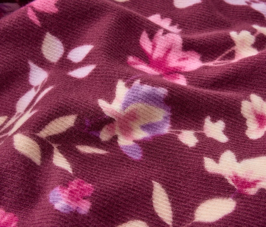 Dunkelroter Stoff mit Blumenmuster in Rosa, Lila und Creme.