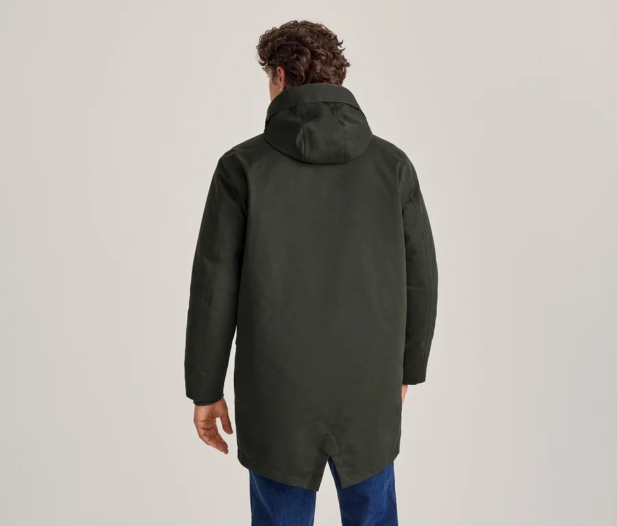 Mann von hinten, der eine dunkelgrüne Kapuzenjacke und blaue Jeans trägt.