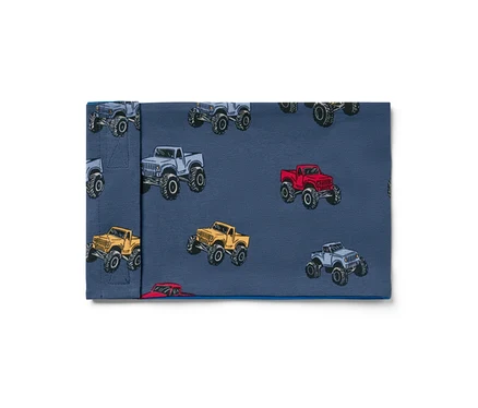 Stoff mit Monstertruck-Muster in Grau, Rot und Gelb auf blauem Hintergrund.
