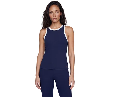 Frau steht in einem marineblauen gerippten Tanktop mit weißem Rand und passenden marineblauen gerippten Leggings vor weißem Hintergrund.