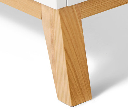 Detail einer weißen Kommode mit hellen Holzbeinen.