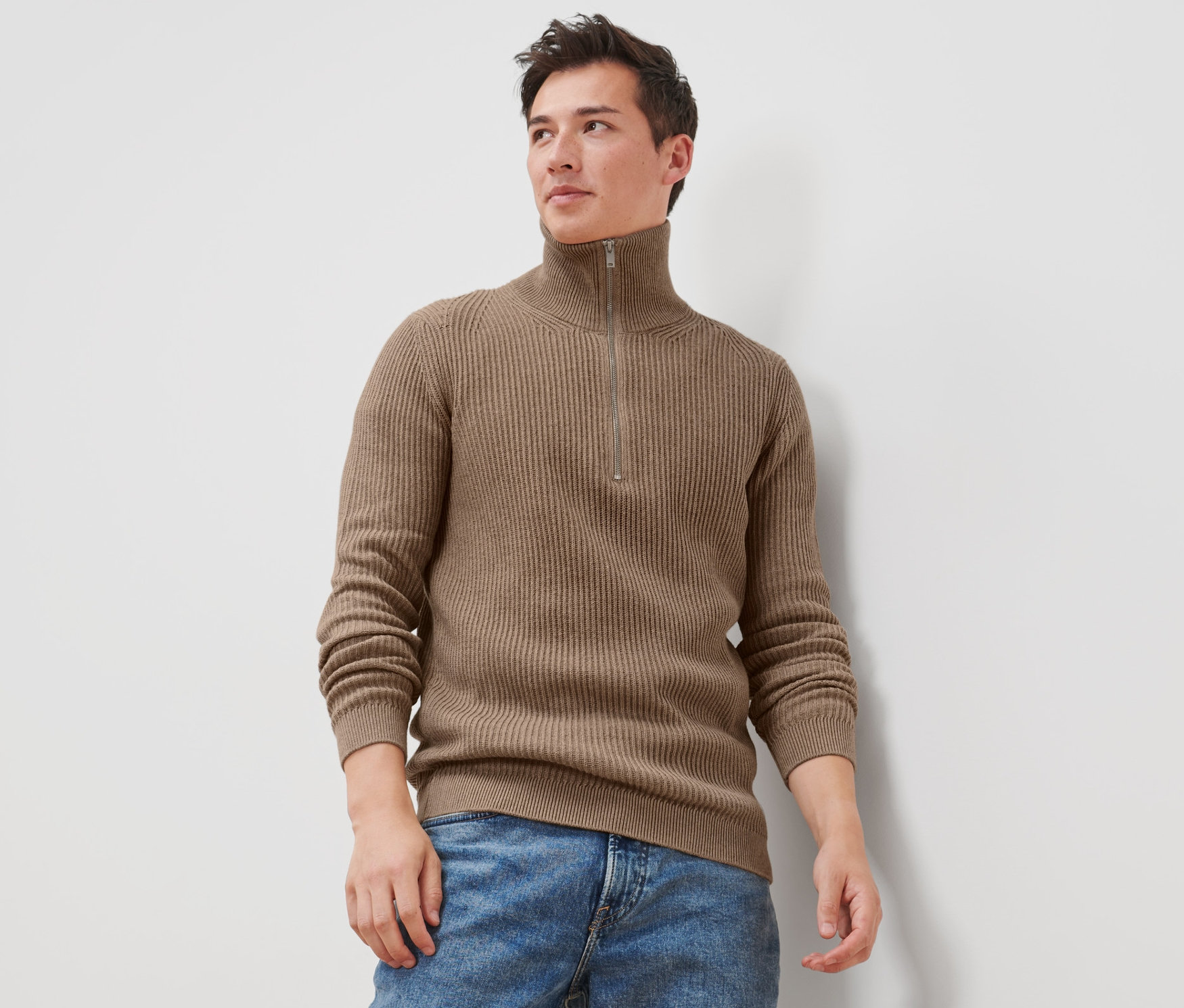 Mann trägt einen Troyer-Pullover und Jeans.