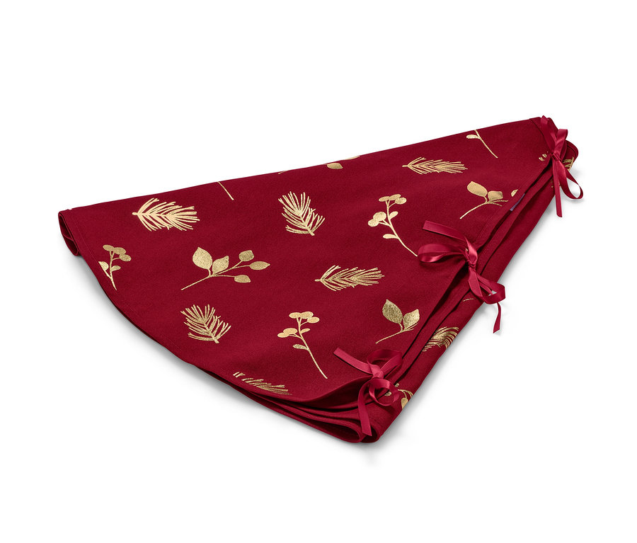 Eine rote Tannenbaumdecke mit goldenen Blättern und Zweigen, die mit roten Bändern zusammengebunden wird.