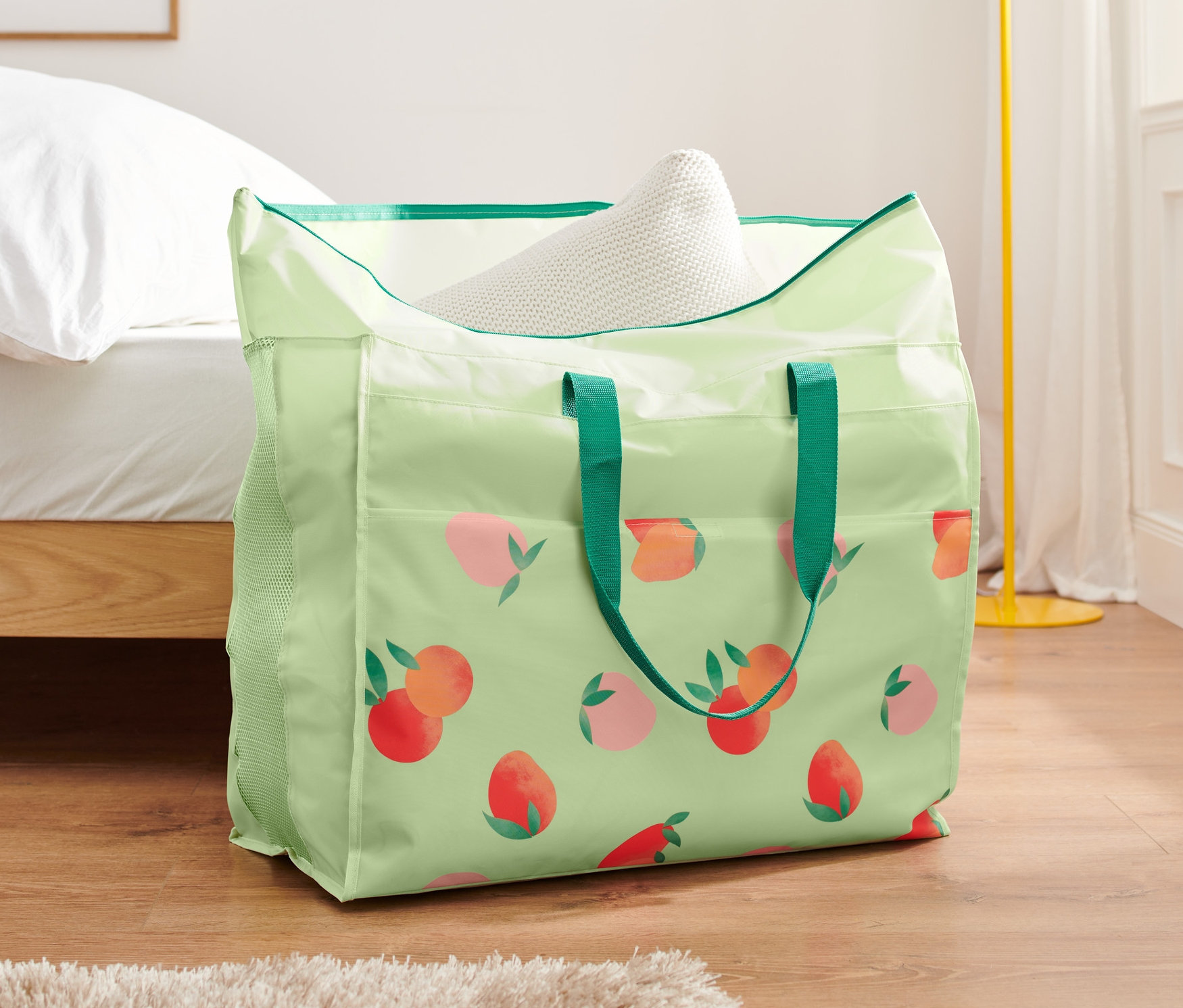 Eine Jumbo-Bettwarentasche mit Pfirsichmuster steht auf dem Boden neben einem Bett.