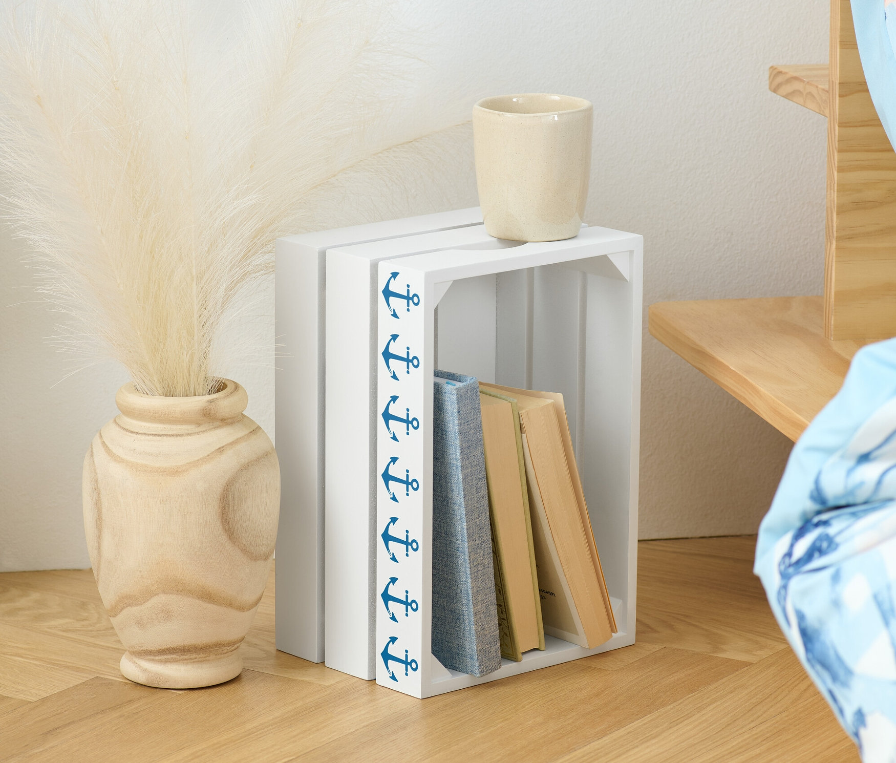 Dekorative Holzkiste mit Büchern, Vase mit Pampasgras und Tasse.