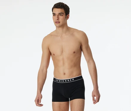 Mann trägt schwarze SCHIESSER Shorts mit weißem Bund.