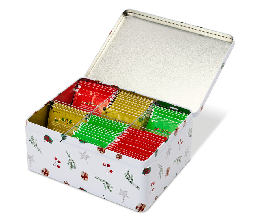 Geöffnete, weiße Blechdose mit Weihnachtsmotiv, gefüllt mit Teebeuteln in Rot, Grün und Gelb.